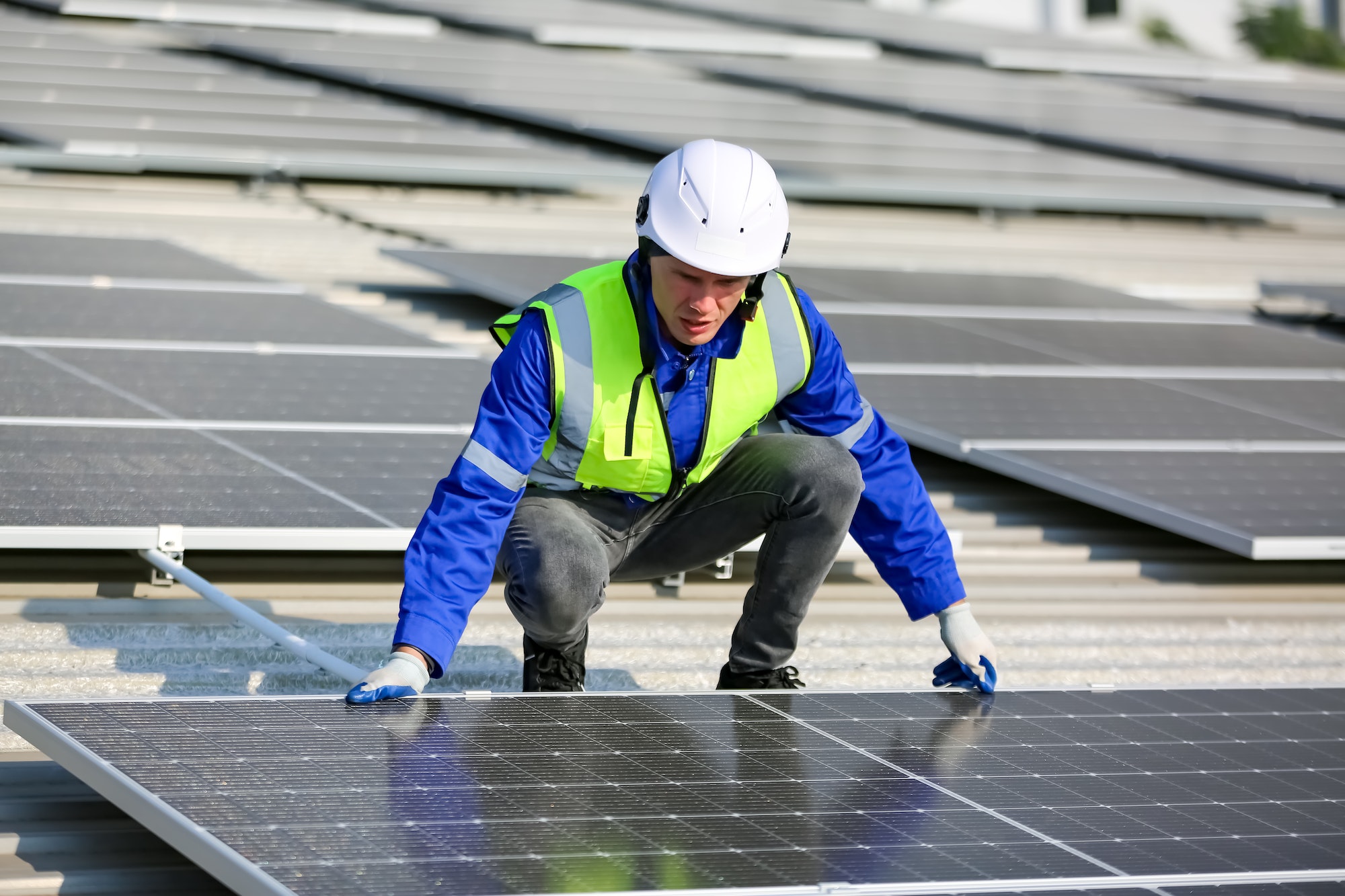 Solar panel installer installing solar panels on roof of warehouse